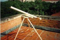 A telescope on a wooden tripod on a rooftop